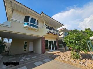 Two-story residential building with a tiled driveway and landscaped front yard