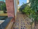 Outdoor pathway with stone tiles and greenery leading to the garden area