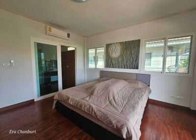 Spacious bedroom with a double bed, wooden floors, and large windows