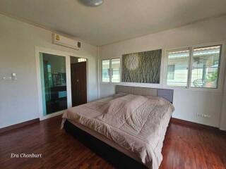 Spacious bedroom with a double bed, wooden floors, and large windows