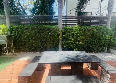 Outdoor seating area with stone table and benches under palm trees