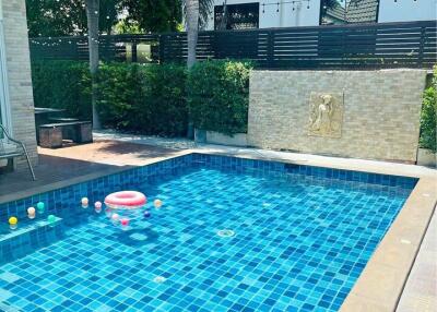 Outdoor swimming pool area with blue-tiled pool and pool toys