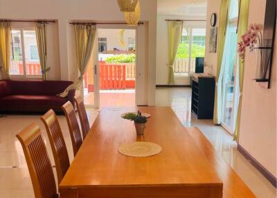 Spacious dining area with wooden table and chairs, natural light and view to living room.