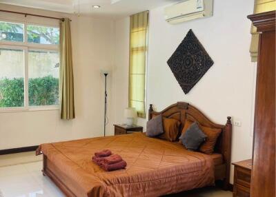 Spacious bedroom with a double bed, ceiling fan, air conditioning, large window, and decorative wall piece