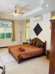 Spacious bedroom with a double bed, ceiling fan, air conditioning, large window, and decorative wall piece