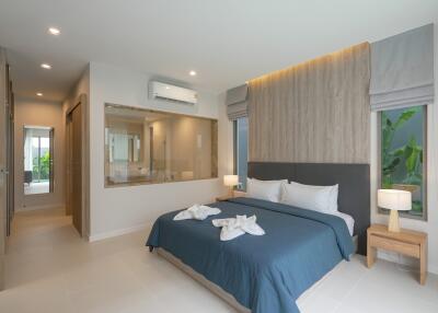 Modern bedroom with king-sized bed, nightstands, lamps, and open view to the bathroom