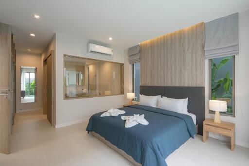 Modern bedroom with king-sized bed, nightstands, lamps, and open view to the bathroom