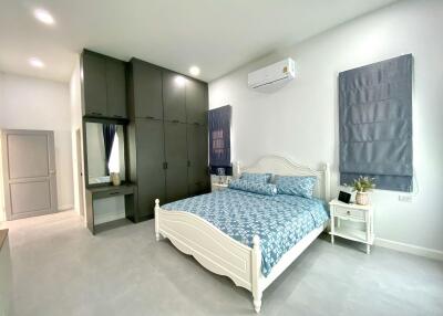 Spacious bedroom with bed, wardrobe, and air conditioner