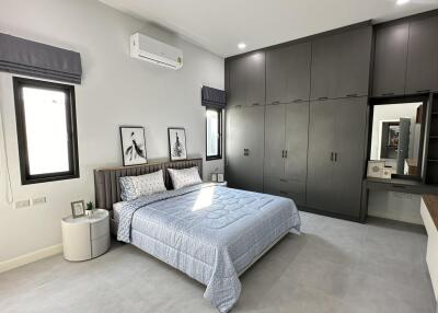 Modern bedroom with gray built-in wardrobes, a large bed, and natural light from windows