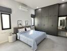 Modern bedroom with gray built-in wardrobes, a large bed, and natural light from windows