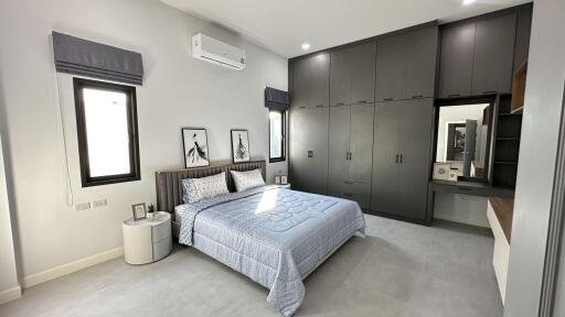 Modern bedroom with gray built-in wardrobes, a large bed, and natural light from windows