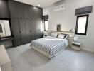 Spacious bedroom with modern decor, large built-in wardrobe, bed and nightstand