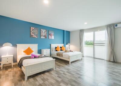 Spacious bedroom with twin beds, blue accent wall, and large windows