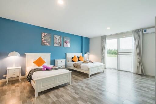 Spacious bedroom with twin beds, blue accent wall, and large windows