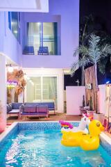 Modern outdoor swimming pool with pool floats and lounge area at night