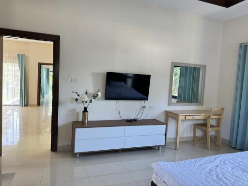 Modern bedroom with a wall-mounted TV, desk, and large window