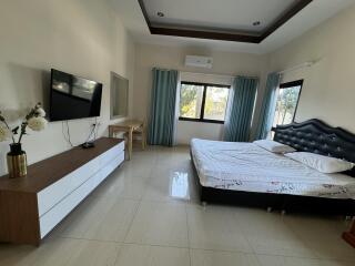 Modern bedroom with large windows, TV, and minimalist furniture