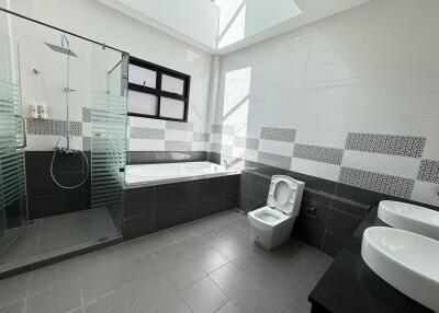 Modern bathroom with bathtub, shower, toilet, and double sinks