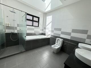 Modern bathroom with bathtub, shower, toilet, and double sinks