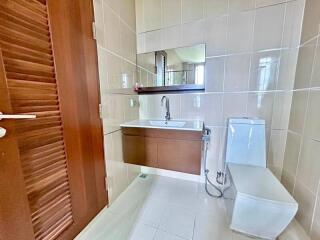 Modern bathroom with wooden door, wall-mounted vanity, large mirror, and toilet