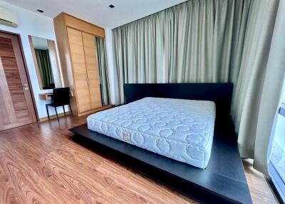 Modern furnished bedroom with wooden floor, large bed, and wardrobe