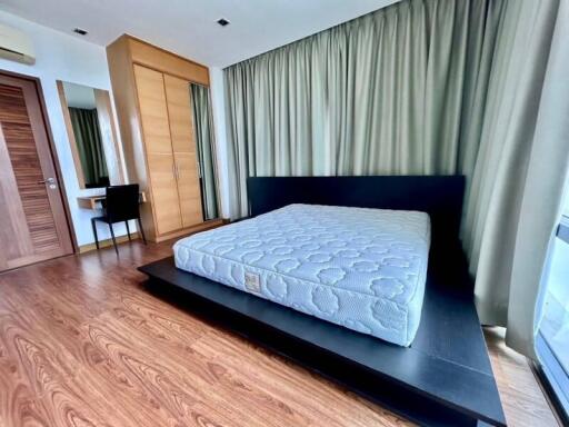 Modern furnished bedroom with wooden floor, large bed, and wardrobe