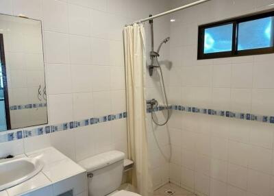 Bathroom with white tiles, shower, toilet, and sink