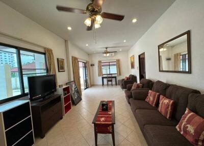 Spacious living room with sofas, a television, ceiling fan, and large windows