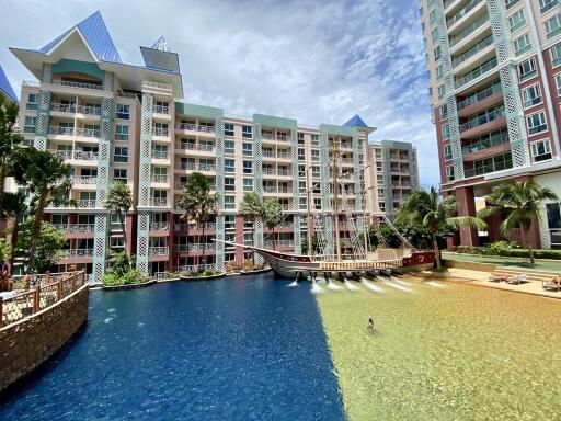 Exterior view of a condominium with swimming pools and a decorative ship