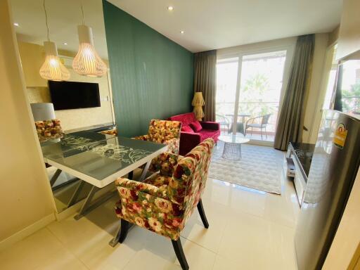 Modern and well-lit living room with dining area, large windows, and a cozy balcony.