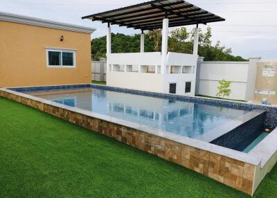 Outdoor swimming pool with artificial lawn and poolside structure