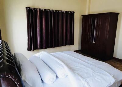 Modern bedroom with bed, pillows, brown curtains, and wardrobe