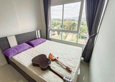 Bedroom with a large window and a bed with two purple pillows