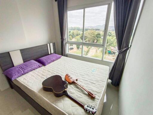 Bedroom with a large window and a bed with two purple pillows