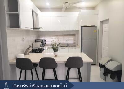 Modern kitchen with white cabinets, refrigerator, and breakfast bar