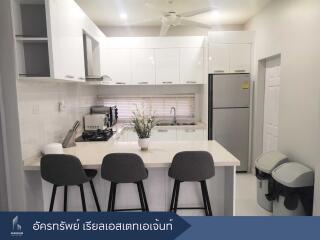 Modern kitchen with white cabinets, refrigerator, and breakfast bar