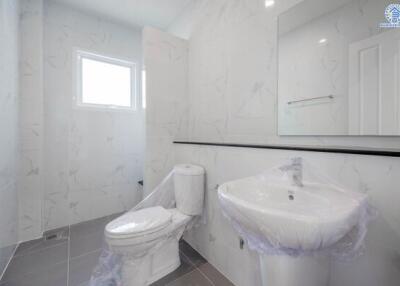 Modern bathroom with white fixtures and marble-tiled walls