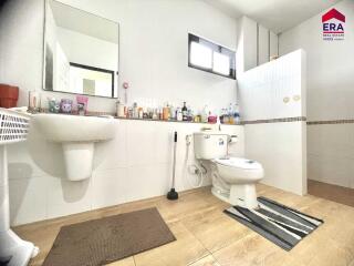 Well-lit bathroom with sink, toilet, window, and tiled floor