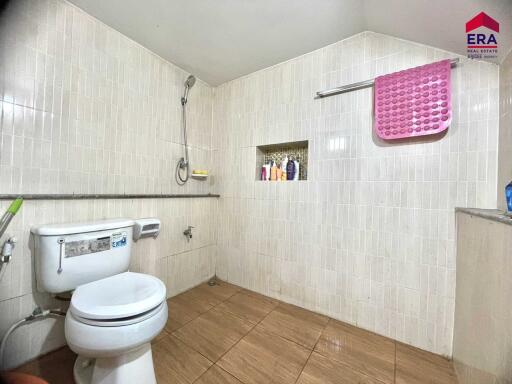 Bathroom with tiled walls and floor, toilet, shower, and towel rack