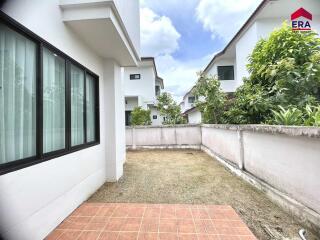 Backyard view of the house with tiled patio and grass patch