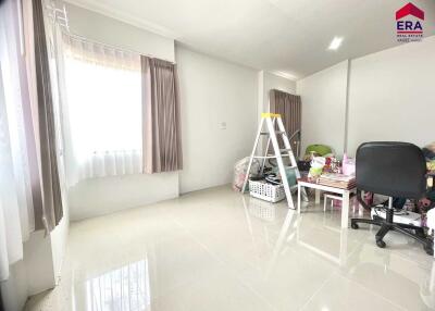 Bright and spacious bedroom with large window, modern tile flooring, and ample space for home office setup.