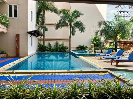 Outdoor swimming pool with poolside chairs and tropical plants