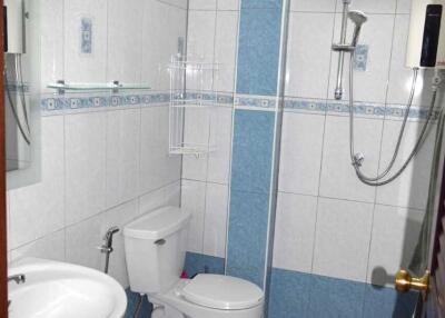 A modern bathroom with white and blue tiles, equipped with a toilet, sink, and shower