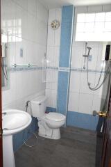 A modern bathroom with white and blue tiles, equipped with a toilet, sink, and shower