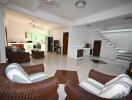 Spacious living area with chairs, tiled floor, and staircase