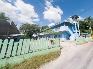 Exterior view of a two-story blue building with adjacent green fence