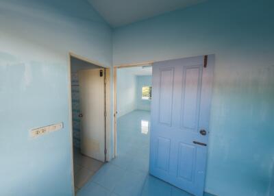 A light blue bedroom with open doors leading to another room.