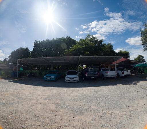 Covered parking area with multiple vehicles under a sunny sky