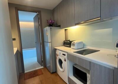 Modern kitchen with appliances including a washing machine, microwave, refrigerator, and stove