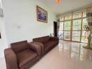 Living room with brown sofa, large windows, and wall painting